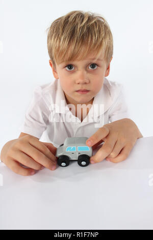 Adorabili poco ragazzo giocando con una piccola auto in legno toy Foto Stock