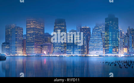 La bellissima skyline di New York City è riflessa nella East River di notte. Fotografato da tutto il fiume al Ponte di Brooklyn Park. Foto Stock