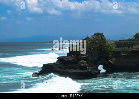 Il paesaggio dell'isola di Bali shore con blu scuro oceano Indiano, onde enormi e scogliera nera con tempio Foto Stock