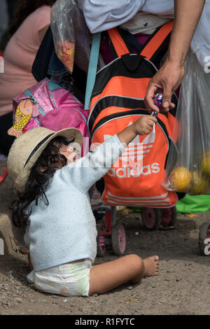 Irapuato, Guanajuato, Messico. 12 Nov 2018. Un giovane rifugiato honduregne con l'America centrale caravan migrante si tramanda una caramella da un volontario come la sua famiglia attende prima di proseguire il viaggio verso nord-ovest verso la frontiera degli Stati Uniti Novembre 12, 2018 a Irapuato, Guanajuato, Messico. Il caravan è stato sulla strada per un mese è a metà strada lungo il loro viaggio a Tijuana. Credito: Planetpix/Alamy Live News Foto Stock