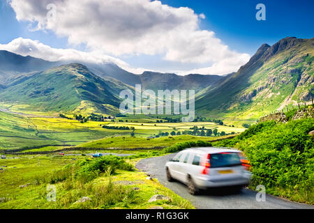Auto in movimento su una strada di campagna al di sopra di grande Langdale valley, con una splendida vista sul quartiere del lago colline, REGNO UNITO Foto Stock