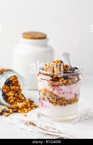 Il Granola al forno, marmellata e yogurt sana colazione parfait in vetro. Una sana detox food concept. Foto Stock