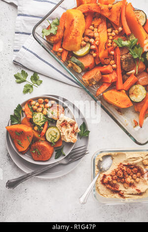 Verdure al forno (carote, zucchine, patate dolci, zucca) e ceci con hummus, vista dall'alto. Impianto basato dieta concetto. Foto Stock