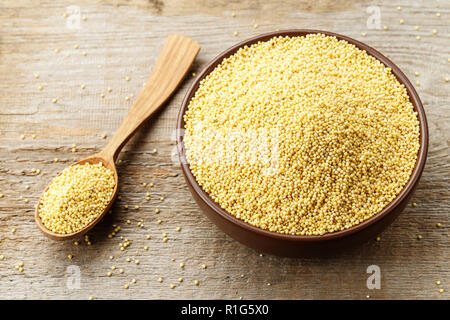 Piastra con cereali grezzi miglio su uno sfondo di legno. preparazione di un utile piatto nutriente Foto Stock