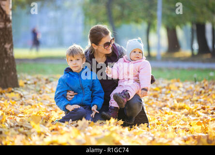 Giovane donna con figlio di età prescolare e baby figlia godendo di una splendida giornata nel parco di autunno Foto Stock