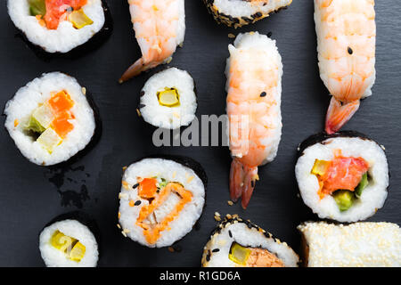 Tipica cucina asiatica impostato su nero ardesia cucina piastra. - Sushi futomaki e nigiri. Pesce crudo con riso e verdure. Foto Stock