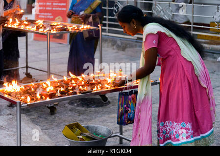 Chennai, India - 18 agosto 2018: una donna di accendere una candela davanti al Signore Shani santuario nel Tempio Kapaleeshwarar per un singolo puja Foto Stock