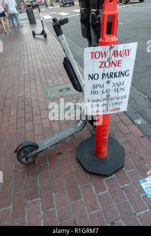 Un calce-S dockless scooter elettrico in modo divertente parcheggiato a fianco di un 'Trainare zona' segno, Gaslight trimestre, San Diego, California, Stati Uniti. Foto Stock