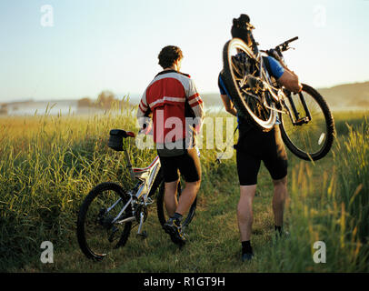 Due maschio passeggiate in montagna le loro biciclette lungo un sentiero. Foto Stock