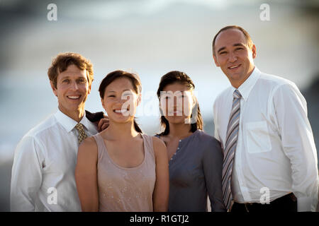 Quattro i dirigenti aziendali in piedi in riva al mare. Foto Stock
