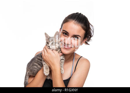 Ragazza adolescente snuggling facce con la sua pelliccia e carino grigio tabby gattino. Foto Stock