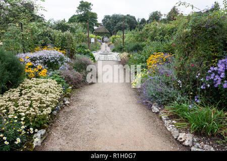 Un sentiero conduce tra fiori colorati delle frontiere nell'orto a West Dean. Foto Stock