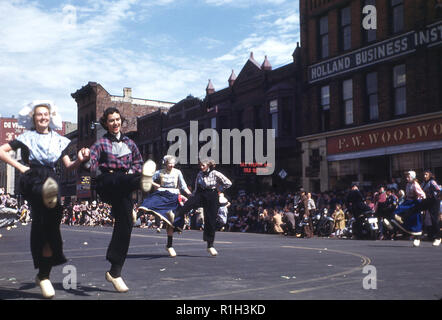 Degli anni Cinquanta, storico, giovani donne che indossano costumi tradizionali e zoccoli Dancing in the street come parte di essi in un corteo per celebrare l'annuale festival del tulipano e la città del patrimonio Olandese, Olanda, Michigan, Stati Uniti d'America. Nel 1847 Holland fu colonizzata da calvinista olandese separatisti, emigrato da Paesi Bassi come un gruppo nel loro desiderio di libertà religiosa e di un migliore futuro economico. Foto Stock