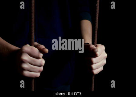 Bambino mani tenendo le barre in un oscuro nascondiglio. Concetto di immagine del bambino sequestrato Foto Stock