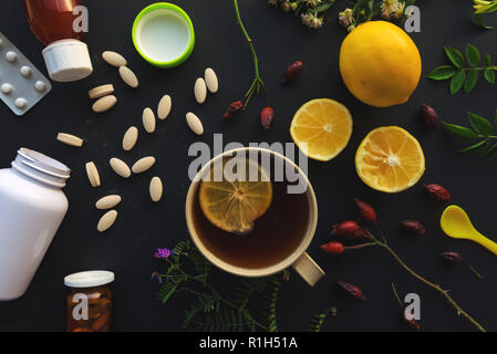 Herbal vs medicina convenzionale concetto, tazza di tè e frutta limone o pillole e farmaci Foto Stock