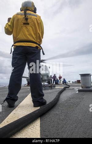 Mare delle Filippine (sett. 19, 2018) marinai condurre una pompa a caldo su un MH-60R Sea Hawk elicottero, assegnato al "Saberhawks" di elicottero Maritime Strike Squadron (HSM) 77, sul ponte di volo dell'Arleigh Burke-class guidato-missile destroyer USS Benfold (DDG 65) durante la Valiant scudo 2018. Valiant shield è un solo negli Stati Uniti, biennale la formazione sul campo di allenamento (FTX) con un focus sulla integrazione di formazione congiunta in un Blu-acqua ambiente tra le forze americane. Questa formazione consente un vero-mondo proficiency nel sostenere forze congiunte attraverso il rilevamento, la localizzazione, tracking e unità di impegno in mare, con l'intelligenza artificiale Foto Stock