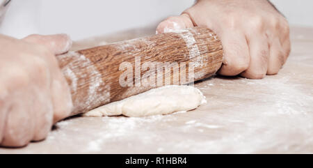 Maschio di rotoli di cucinare la pasta con il matterello, mani closeup Foto Stock