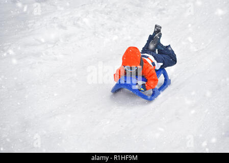 Little Boy correre sulla neve slitte in inverno Foto Stock