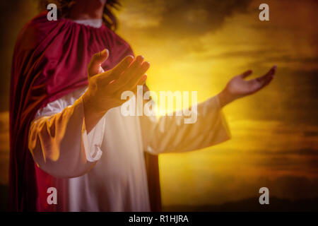 Gesù Cristo alzando le mani e pregando con sfondo al tramonto Foto Stock