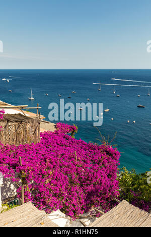 Positano incorniciato da rosa bouganville e barche in background. Colorato Positano, la perla della Costiera Amalfitana, con le sue case multicolori e Foto Stock