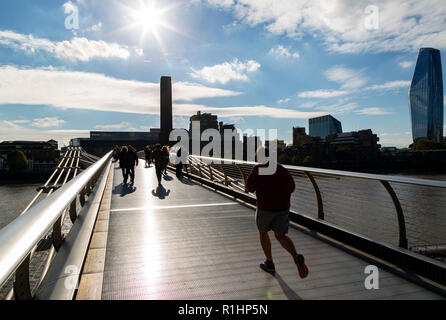 Un uomo lo jogging e la gente camminare sopra il Millennium Bridge (ponte traballante) London, guardando verso la Tate Modern Foto Stock