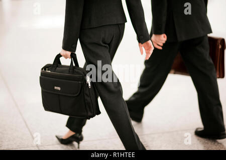 Foto ritagliata di imprenditore e la donna che la porta valigette. Foto Stock