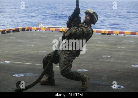 Col. Robert Brodie, Comandante del trentunesimo Marine Expeditionary Unit, si stabilizza se stesso sul ponte dell'assalto anfibio nave USS Wasp (LHD 1) durante la rapida formazione di corda a bordo della Vespa, in corso nell'Oceano Pacifico, Sett. 19, 2018. Fast roping consente di Marines per entrare altrimenti luoghi inaccessibili dall'alto. Il trentunesimo MEU, il Marine Corps' solo in modo continuo distribuita MEU, fornisce una forza flessibile pronto per eseguire una vasta gamma di operazioni militari nella regione Indo-Pacifico. Foto Stock