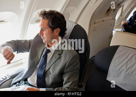 Imprenditore controllando il tempo durante un volo. Foto Stock