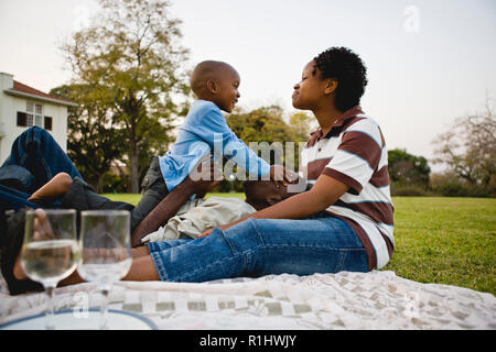 Mid-adulto giovane seduto avente un picnic con il loro bambino figlio. Foto Stock