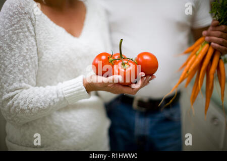 Giovane Azienda un nuovo mazzo di carote e pomodori nelle loro mani. Foto Stock