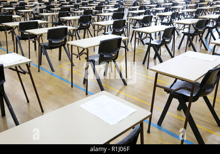 Vista di una grande sala esame sala esame e scrivanie tavoli allineati in file pronto per gli studenti di una scuola superiore di venire e sedersi i loro esami carta per prove Foto Stock