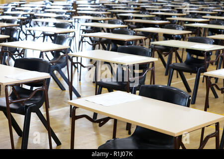 Vista di una grande sala esame sala esame e scrivanie tavoli allineati in file pronto per gli studenti di una scuola superiore di venire e sedersi i loro esami carta per prove Foto Stock