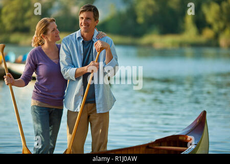 Felice Coppia di mezza età in piedi con le loro canoe vicino a un lago. Foto Stock