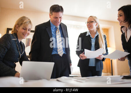 Tre imprenditrici e un collega di sesso maschile che lavorano insieme in una stanza di un hotel per un viaggio di lavoro. Foto Stock