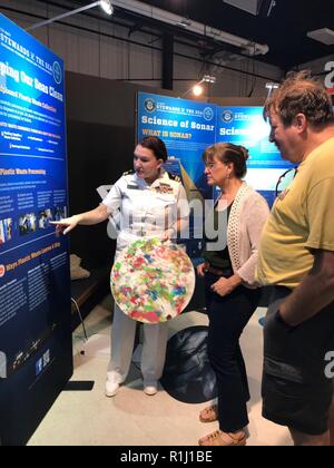 WALLOPS ISLAND, Va. (sett. 22, 2018) Lt. Jill Brown, un public affairs officer attaccata alla U.S. Le forze della flotta comando, spiega a bordo dei rifiuti di plastica di elaborazione per visitatori presso l'U.S. Marina "Custodi del mare: difendendo la libertà, tutela dell'ambiente" presentano durante la NASA il sessantesimo anniversario tenutosi presso la NASA Wallops Flight Facility Centro Visitatori. La Marina Militare si avvale di tutti i mezzi a disposizione per attenuare il potenziale impatto ambientale delle nostre attività senza mettere a repentaglio la sicurezza dei nostri marinai o influenzare la nostra marina disponibilità mission. Foto Stock