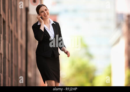 Imprenditrice passeggiate all'aperto parlando di un cellulare. Foto Stock