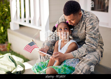 Sorridente ragazza seduta con suo padre sulla parte anteriore fasi della loro casa. Foto Stock