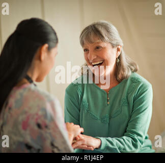 Sorridente giovane infermiere consolante una donna senior. Foto Stock