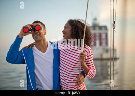 Felice coppia giovane divertendosi con un binocolo mentre la vela. Foto Stock