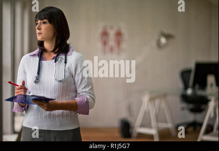 Ritratto di un giovane medico donna tenendo un clipboard nel suo ufficio. Foto Stock