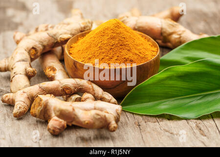 La curcuma in polvere in ciotole di legno sul tavolo di legno Foto Stock