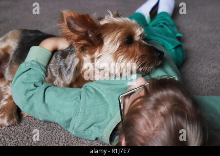 Bambino cuddling con il loro miglior amico Foto Stock