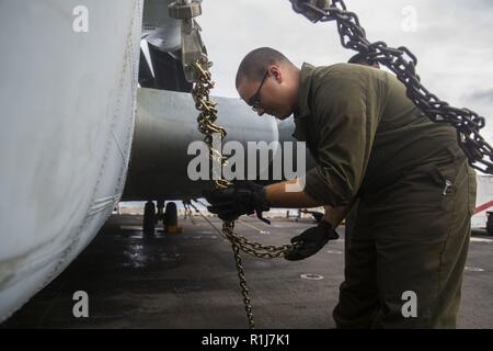Cpl. Elija Thomas controlla la sicurezza di legare le catene per i velivoli come manutenzione preventiva a bordo della USS Iwo Jima, 7 ottobre. La manutenzione preventiva è condotta per sostenere il funzionamento ottimale per i velivoli che partecipano in esercizio Trident frangente 18. Trident frangente è un led NATO esercizio in cui la ventiquattresima Marine Expeditionary Unit e il combattimento aereo elemento avrà un ruolo di primo piano come un mare-basato MAGTF. Christeas è un CH-53 capo equipaggio con HMH-366. Foto Stock