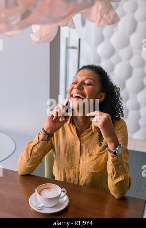 Curly donna ridere parlare al telefono con un amico Foto Stock