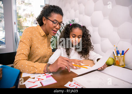 Smart caring insegnante insegnamento prescolare carina ragazza la lettura e la scrittura Foto Stock