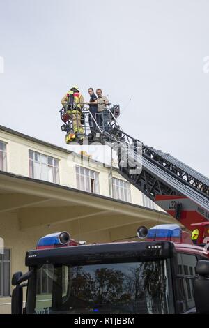 Stati Uniti Esercito vigili del fuoco civili dalla U.S. Army Garrison (USAG) Ansbach dimostrare evacuazione e salvataggio procedure al battaglione e quartier generale di brigata a Storck Baracks in Illesheim, Germania, 10 ottobre, 2018. La dimostrazione è parte del presidio di ricorrenza annuale per la prevenzione degli incendi e per la settimana. Foto Stock