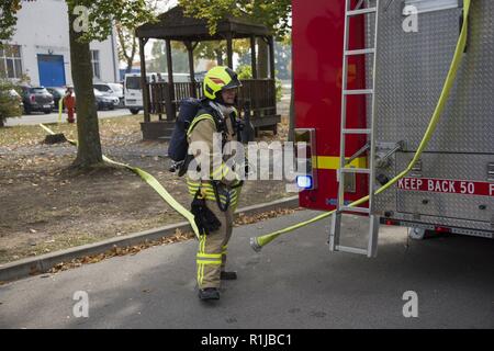 Stati Uniti Esercito vigili del fuoco civili dalla U.S. Army Garrison (USAG) Ansbach dimostrare evacuazione e salvataggio procedure al battaglione e quartier generale di brigata a Storck Baracks in Illesheim, Germania, 10 ottobre, 2018. La dimostrazione è parte del presidio di ricorrenza annuale per la prevenzione degli incendi e per la settimana. Foto Stock