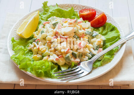 Insalata con bastoncini di granchio, il mais dolce, cetriolo, uova e maionese sul tavolo luminoso. Foto Stock