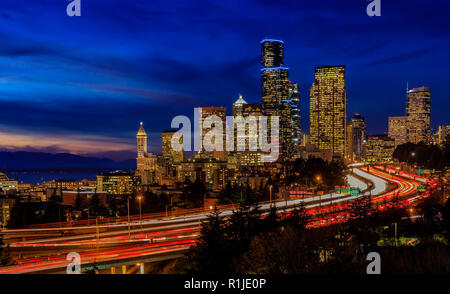 Seattle Downtown skyline e grattacieli oltre I-5 I-90 Interscambio superstrada dopo il tramonto alle ore blu con una lunga esposizione traffico luci trail fr Foto Stock