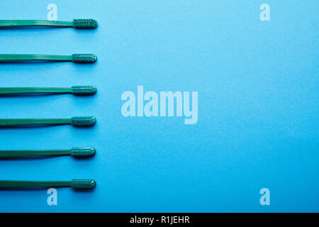 Piatto con laici spazzolini da denti disposti su sfondo blu Foto Stock